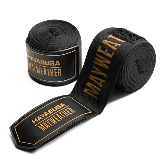 De Hayabusa Mayweather Bandages Zwart Goud combineren luxe en prestatie. Deze elastische handwraps bieden optimale ondersteuning en polsstabiliteit tijdens bokstrainingen, met een stijlvol zwart-gouden design geïnspireerd door kampioenen.