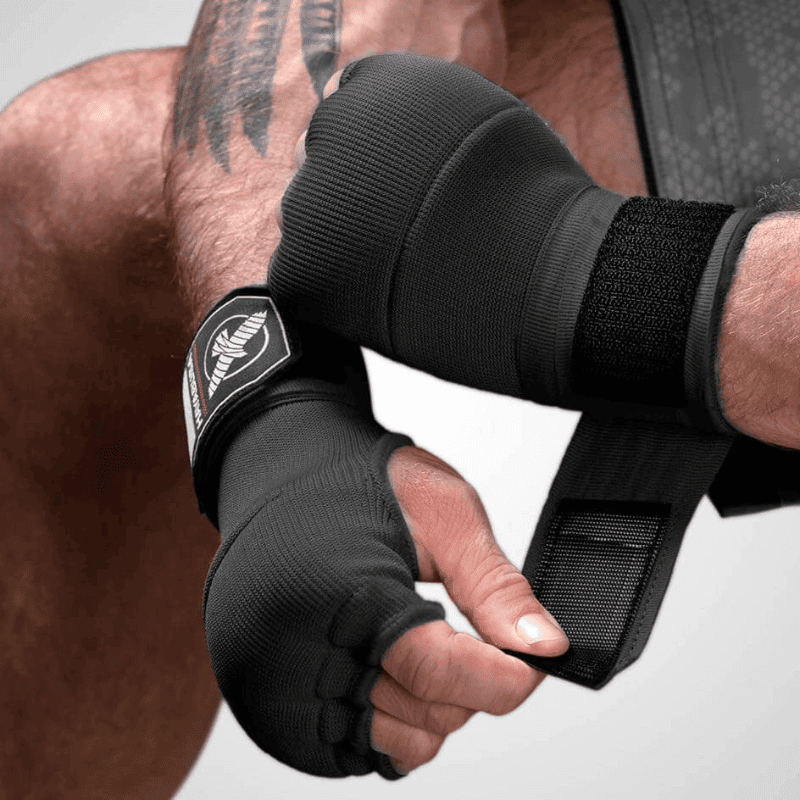 Close-up van iemand die een zwarte Hayabusa Quick Gel Wrap binnenhandschoen aantrekt.