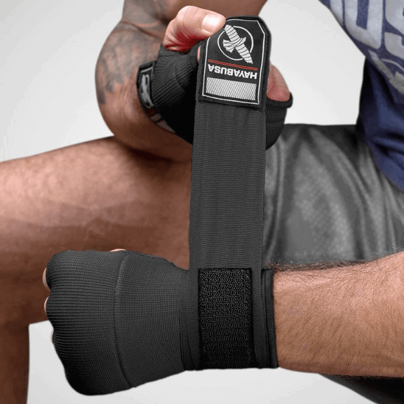 Iemand draagt zwarte Hayabusa binnenhandschoenen Quick Gel Wraps, close-up van de bevestigde handschoen.