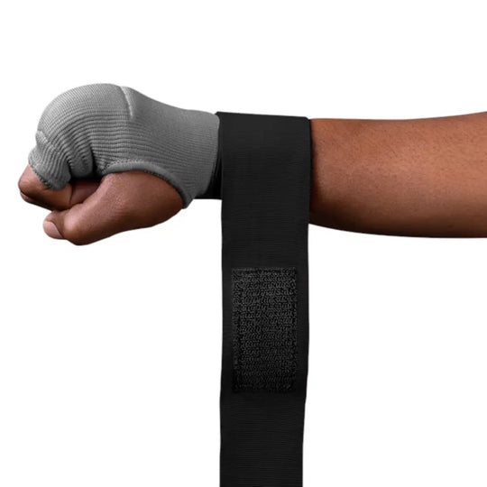 Close-up van een gebalde vuist met een grijze vingerloze binnenhandschoen en een lange, zwarte polsbandage met het klittenbandgedeelte dat naar beneden hangt