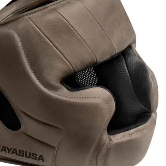 Zijaanzicht van een bruine Hayabusa bokshoofdbeschermer met zwart gaas bij de ademopening en stevige padding rond het gezicht.