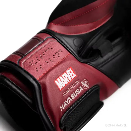Close-up van de rode en zwarte Hayabusa Daredevil bokshandschoen, met de branding MARVEL 'Powered by Hayabusa' en het woord 'DAREDEVIL' in Braille op de manchet.