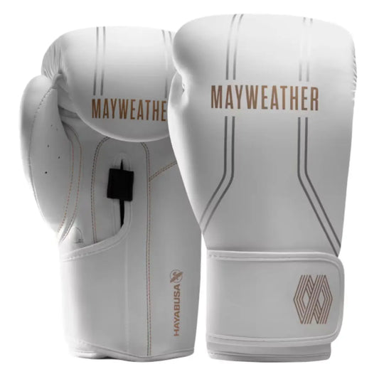 Een paar witte boks- of MMA-handschoenen met het goudkleurige Mayweather-logo staat rechtop tegen een witte achtergrond. De handschoenen hebben zilveren streepdetails en het Hayabusa logo is subtiel zichtbaar op de manchet van de linkerhandschoen.