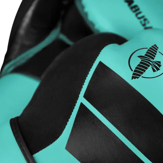 Detailfoto van het Hayabusa logo en zwarte accenten op de knokkels van een turquoise bokshandschoen, met zichtbare stiknaden en textuur.