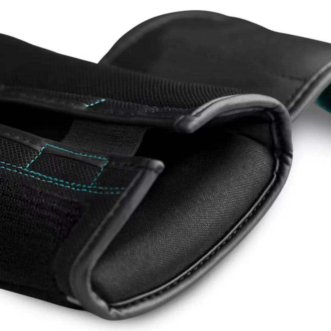 Close-up van de polsband van een zwarte bokshandschoen met klittenband en opvallende turquoise stiknaden, met zichtbare textuur van het materiaal en de afwerking.