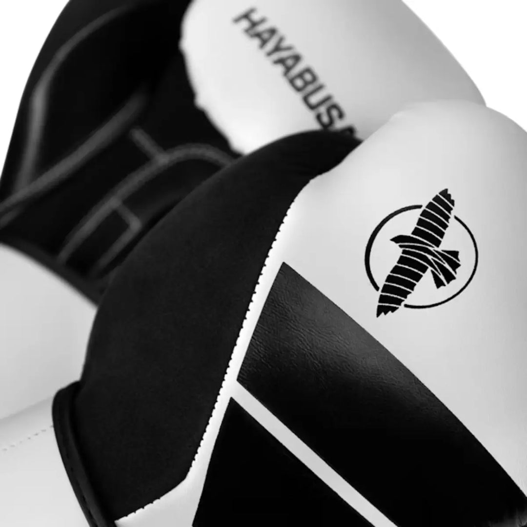 Close-up van witte en zwarte Hayabusa bokshandschoenen met zichtbaar logo en stiksels.