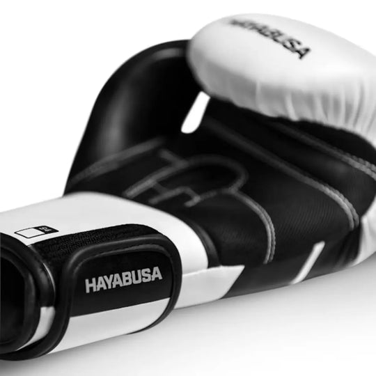 Close-up van Hayabusa bokshandschoen in zwart-wit met witte details en klittenbandsluiting.