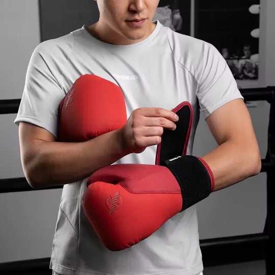 Kickbokser met rode Hayabusa T3 bokshandschoenen die de polssluiting vastmaakt tijdens training in de sportschool.