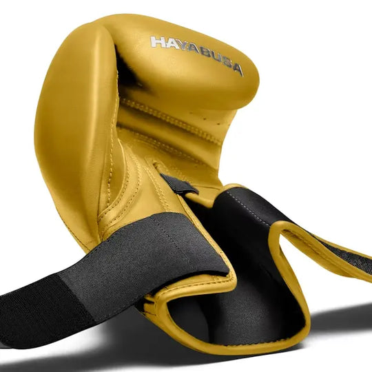 Close-up van een gele Hayabusa bokshandschoen met open polssluiting, zwart klittenband en zichtbaar logo, ontworpen voor maximale ondersteuning.