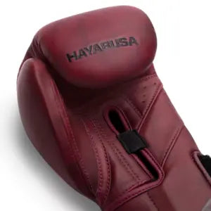  Close-up van de knokkel van een bordeauxrode Hayabusa bokshandschoen, met de naam "HAYABUSA" duidelijk in zwart op het leer gestempeld.