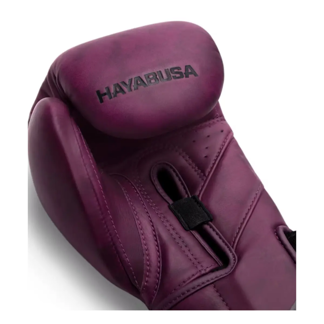 Close-up van paarse Hayabusa bokshandschoen met zichtbaar stiksel, ventilatiegaatjes en zwart logo op de knokkel.