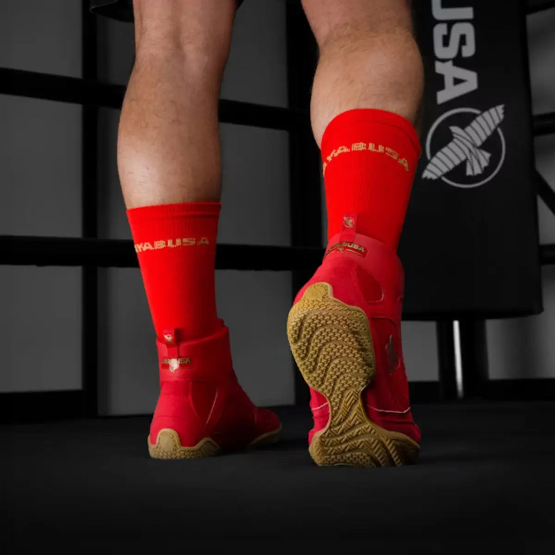 Achteraanzicht van rode Hayabusa boksschoenen met bruine zolen gedragen met rode sokken in gym met Hayabusa branding.