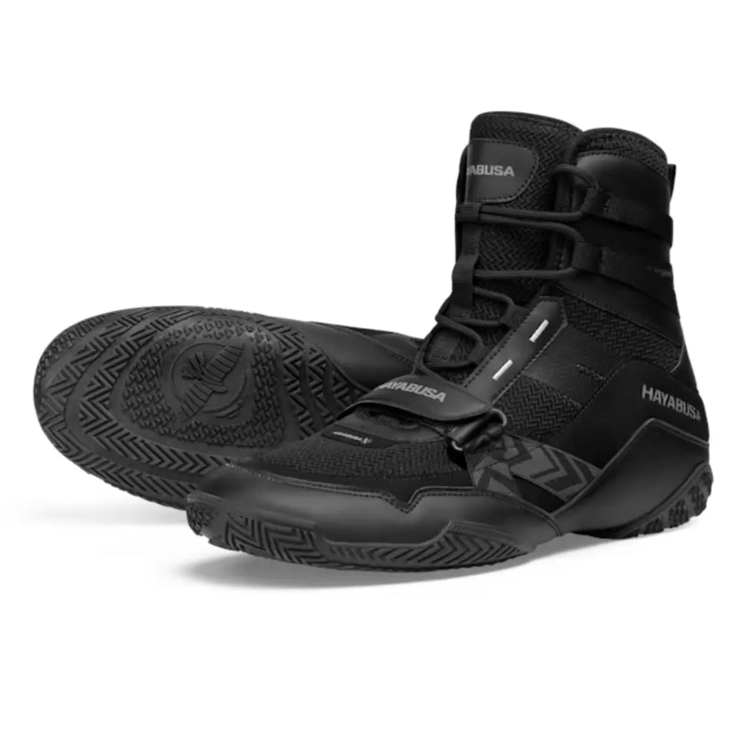 Vooraanzicht van de zwarte Hayabusa boksschoenen met hoge enkelondersteuning, stevige zool met grip en verstelbare strap, ontworpen voor stabiliteit en snelheid tijdens bokstraining.