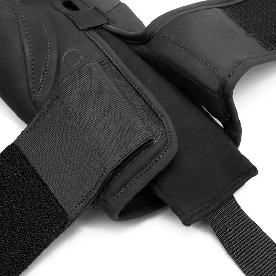 Close-up van een zwarte bandage met klittenband en een lus voor de duim, gemaakt van ademend materiaal voor optimale ondersteuning tijdens vechtsporttrainingen.