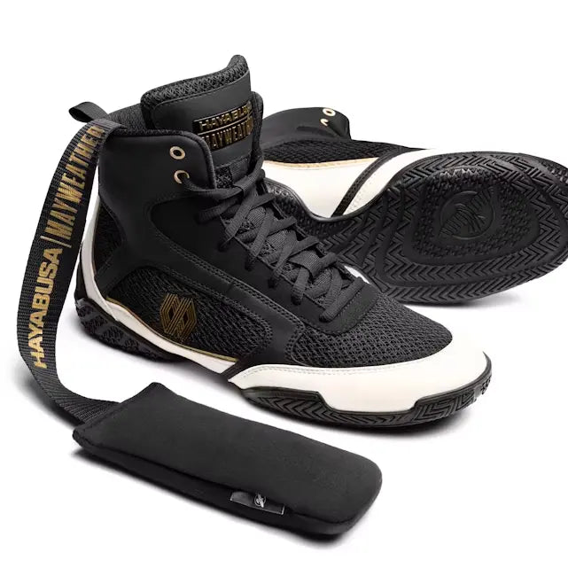Zwarte en witte Hayabusa Mayweather boksschoenen met gouden accenten, inclusief een losse, zwarte tongpad met een Hayabusa-logo.
