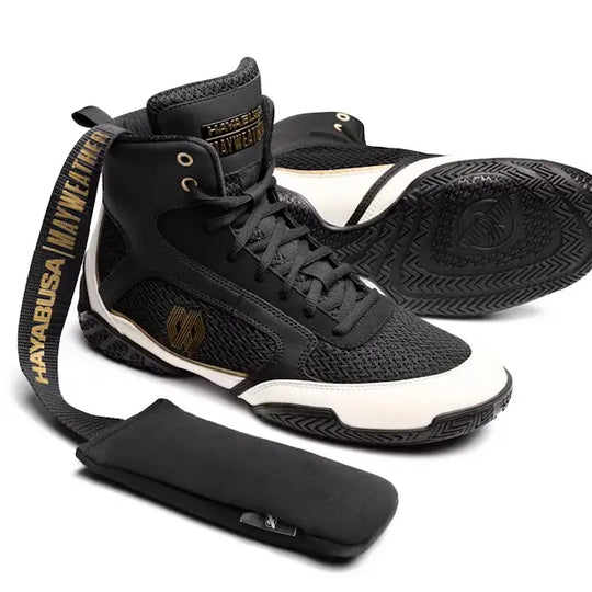 Zwarte en witte Hayabusa Mayweather boksschoenen met gouden accenten, inclusief een losse, zwarte tongpad met een Hayabusa-logo.