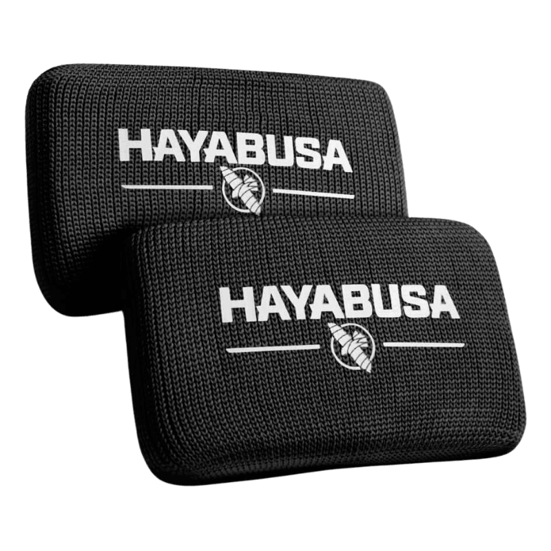 Twee zwarte Hayabusa Boxing Knuckle Guards met het Hayabusa-logo en het adelaarsembleem in wit, gestapeld op een donkere achtergrond.