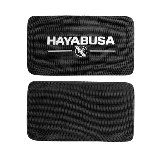 Een enkele zwarte Hayabusa Boxing Knuckle Guard met een zichtbaar wit Hayabusa-logo en adelaarsembleem, gepresenteerd tegen een donkere achtergrond.