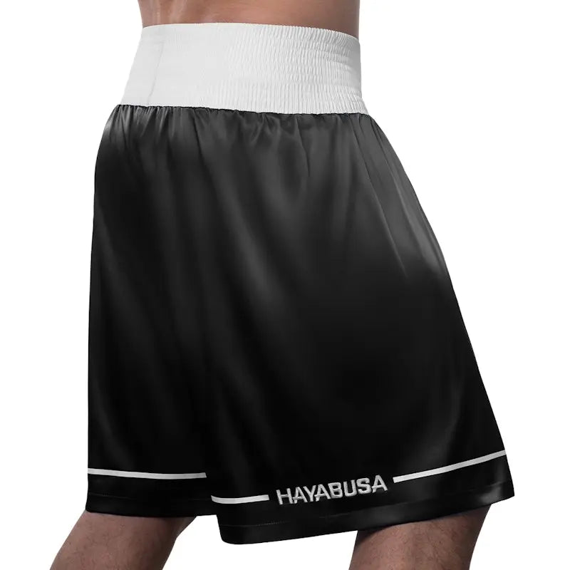 Back view of black Hayabusa boxing shorts with a wide white waistband and subtle white accent lines along the hem. The smooth, lightweight fabric and clean rear design highlight comfort, freedom of movement, and a classic boxing look.