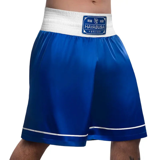 Front view of blue Hayabusa boxing shorts featuring a wide white elastic waistband with the Hayabusa Boxing patch. The lightweight satin-style fabric and white trim along the hem provide a classic boxing look with optimal comfort and freedom of movement for training and competition.