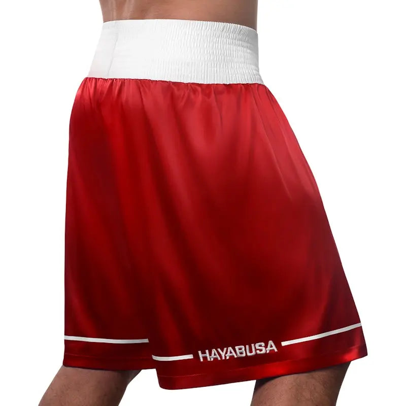 Rear view of red Hayabusa boxing shorts with a wide white elastic waistband and subtle white trim along the hem. The image shows the smooth satin finish, relaxed fit, and clean stitching, highlighting comfort, freedom of movement, and a classic boxing look for training and gym sessions.