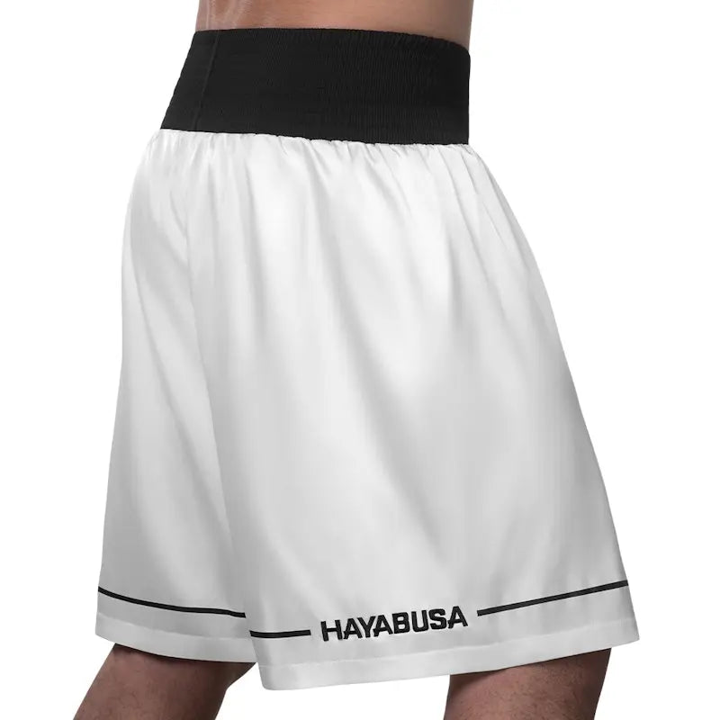 Back view of white Hayabusa boxing shorts with a wide black elastic waistband and subtle Hayabusa branding near the hem. The image highlights the clean design, relaxed fit, and lightweight construction that supports freedom of movement. Designed for comfort and stability during boxing training and intense gym sessions.