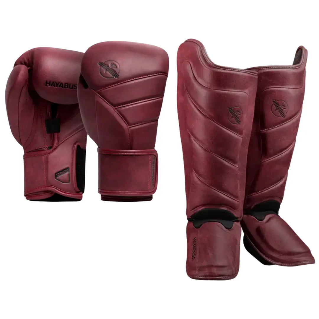 Set van rode Hayabusa bokshandschoenen en scheenbeschermers met zwart logo, perfect voor kickboksen en MMA training.