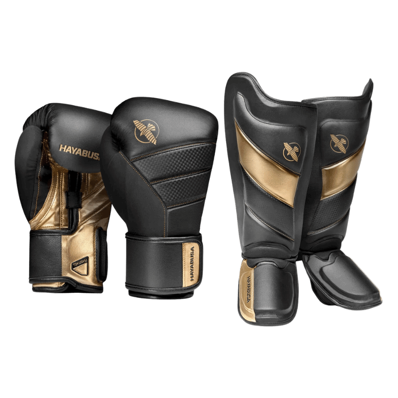 Een paar zwarte en gouden Hayabusa bokshandschoenen en scheenbeschermers, gericht op gevechtssport.