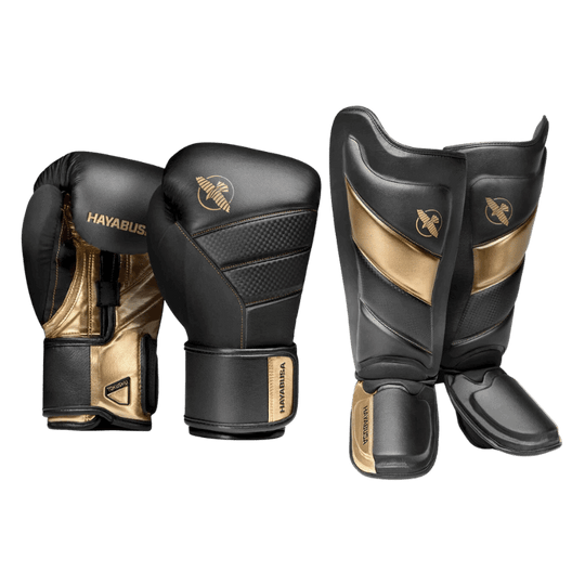 Een paar zwarte en gouden Hayabusa bokshandschoenen en scheenbeschermers, gericht op gevechtssport.