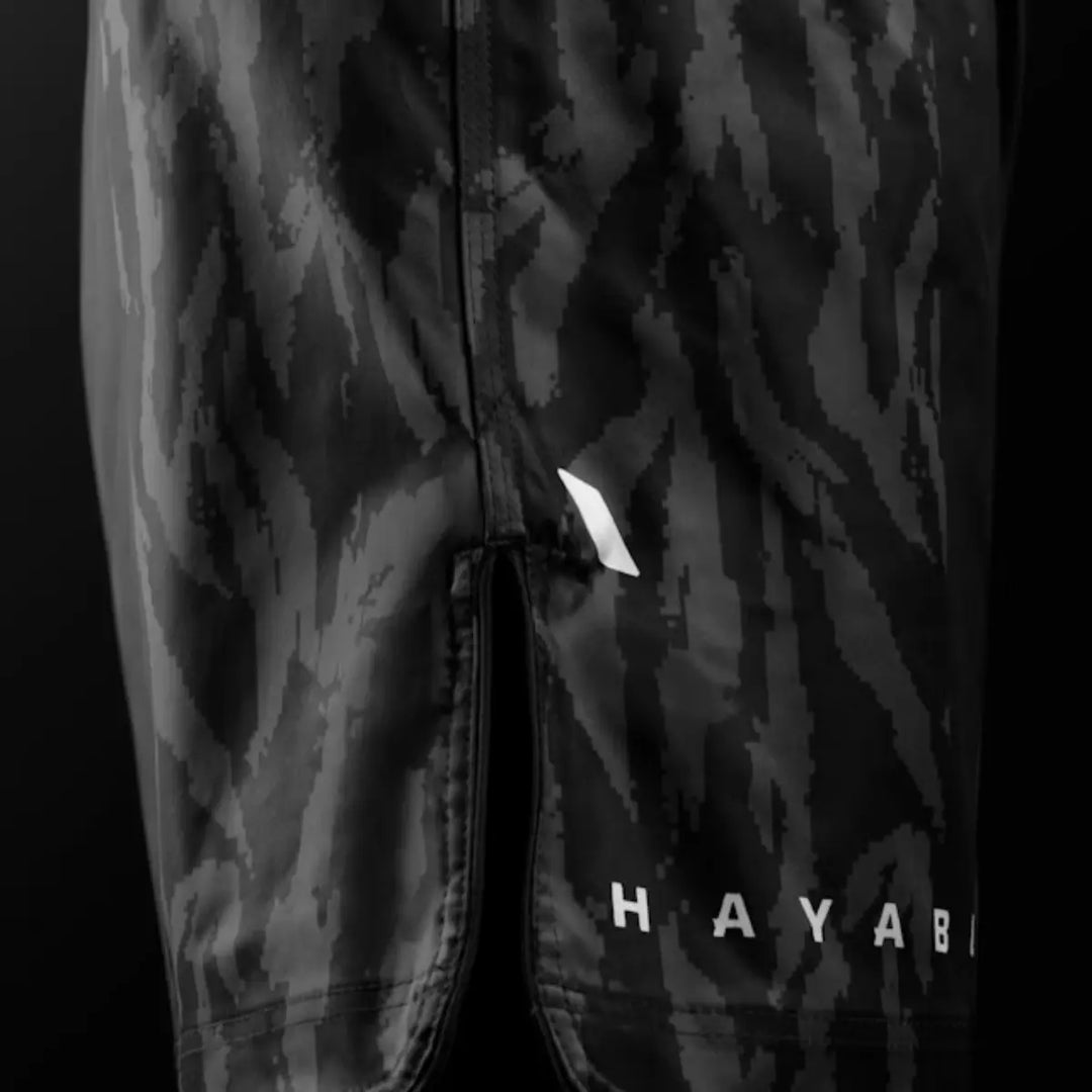 Close-up van zwarte Hayabusa fightshorts met camouflagepatroon en split voor optimale bewegingsvrijheid.
