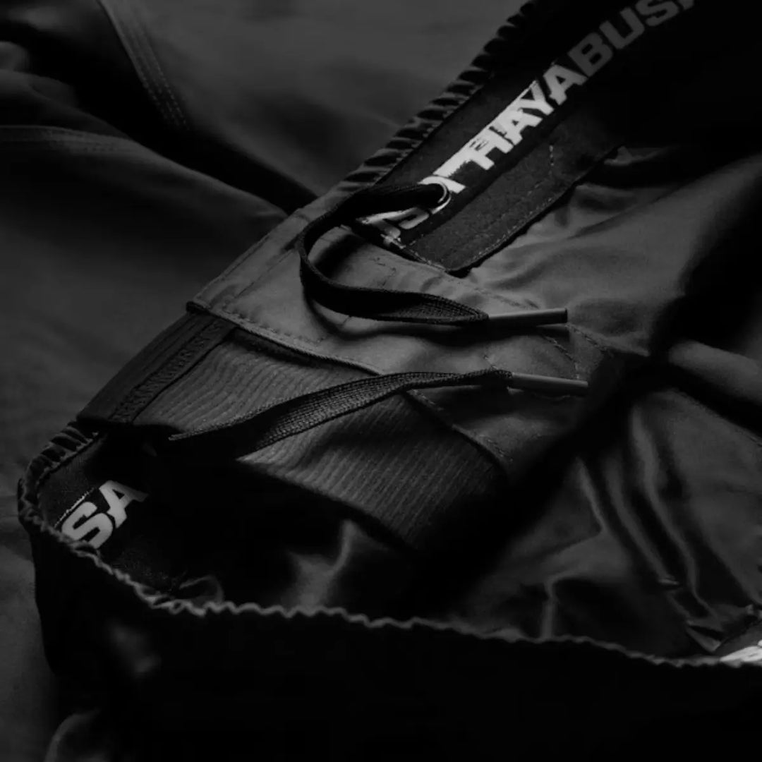 Close-up van de tailleband van zwarte Hayabusa fightshorts met vetersluiting en zichtbaar merklogo aan de binnenzijde.