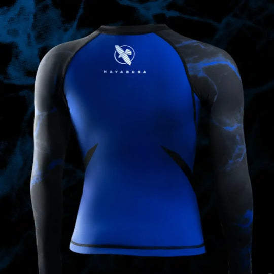 Achteraanzicht van de UFC BJJ Women’s Rashguard in zwart en helder blauw. Het Hayabusa-logo staat centraal bovenaan de rug, duidelijk contrasterend met de blauwe basis. De anatomische lijnen en panelen benadrukken een strakke, sportieve pasvorm.