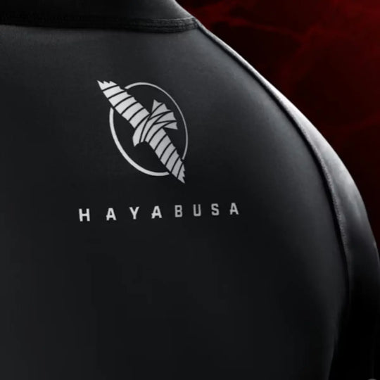 Detailafbeelding van de rug van een zwarte Hayabusa rashguard, met het witte Hayabusa-logo centraal zichtbaar op een strakke, matte stof.
