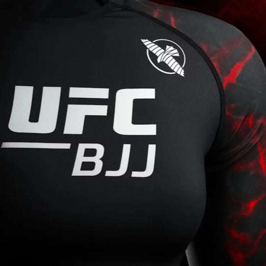 Close-up van de borst van de rashguard, met groot wit UFC BJJ-logo en rode accenten op de mouwen.