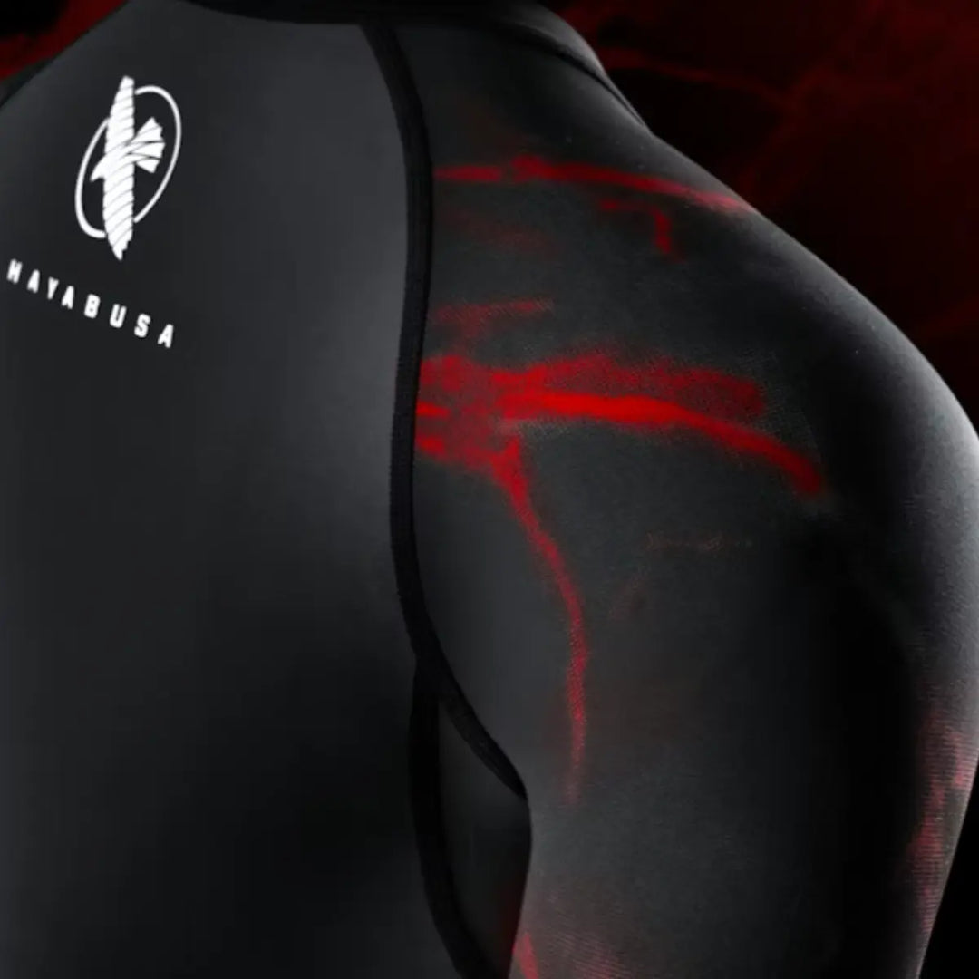 Close-up van de schouder van een zwarte Hayabusa rashguard met rode lightning-patronen en het Hayabusa-logo op de bovenrug.