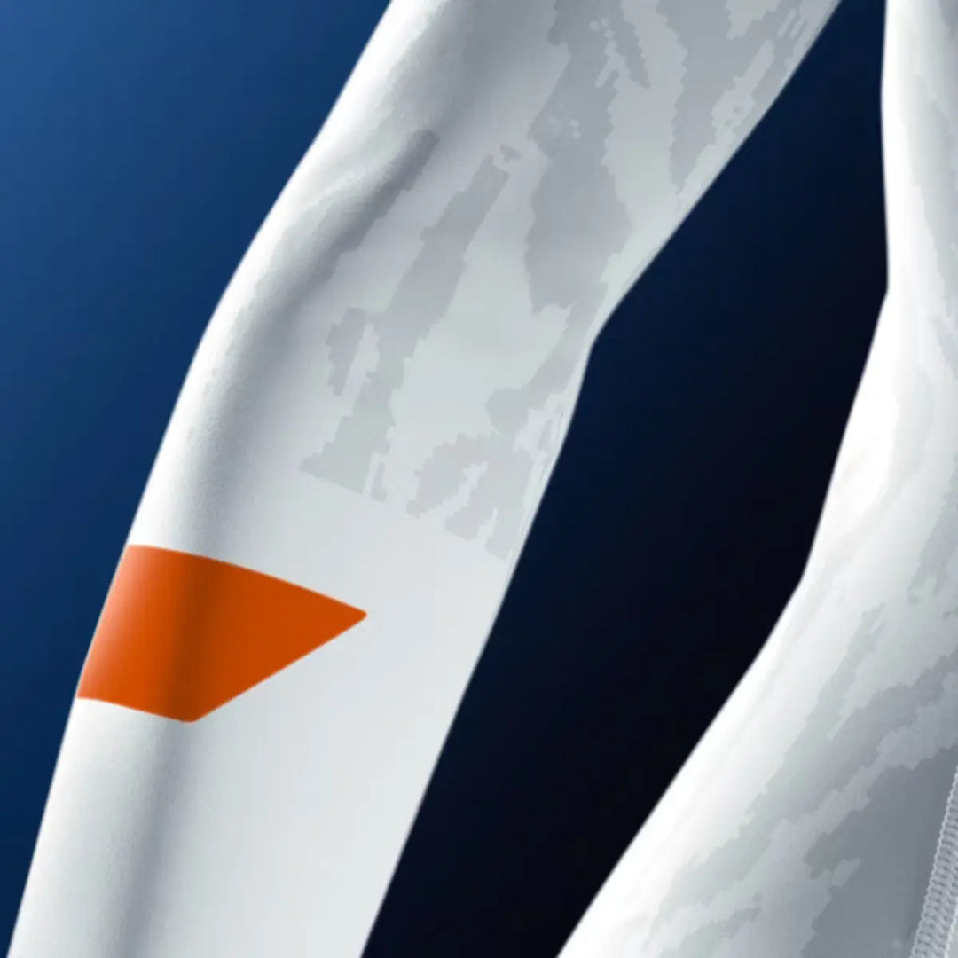 Close-up van de mouw van een witte Hayabusa rashguard met oranje detail en subtiel camouflagemotief.