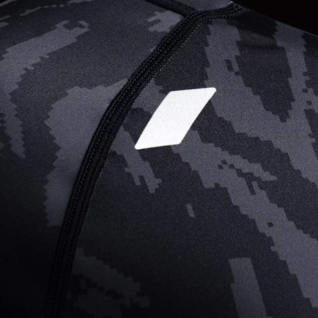 Close-up van zwarte rashguard met camo-patroon en wit geometrisch logo op de borst.