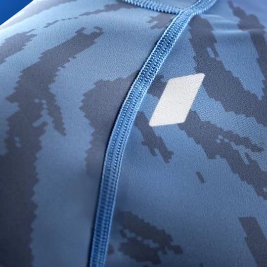 Close-up van blauwe Hayabusa rashguard met camouflageprint en wit logo.