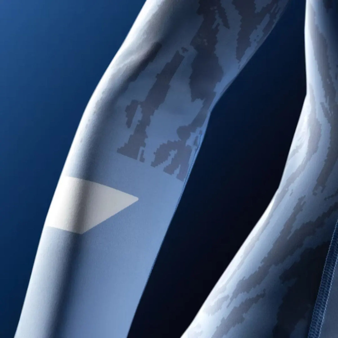 Close-up van blauwe Hayabusa rashguard mouw met camouflageprint en wit logo.