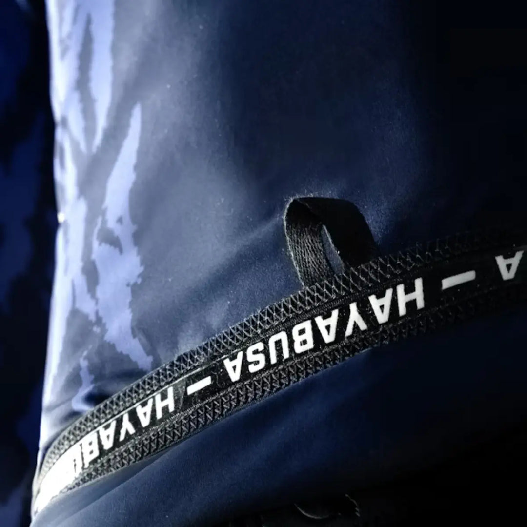Close-up van blauwe Hayabusa rashguard met zwarte zoom en wit logo op de elastische band