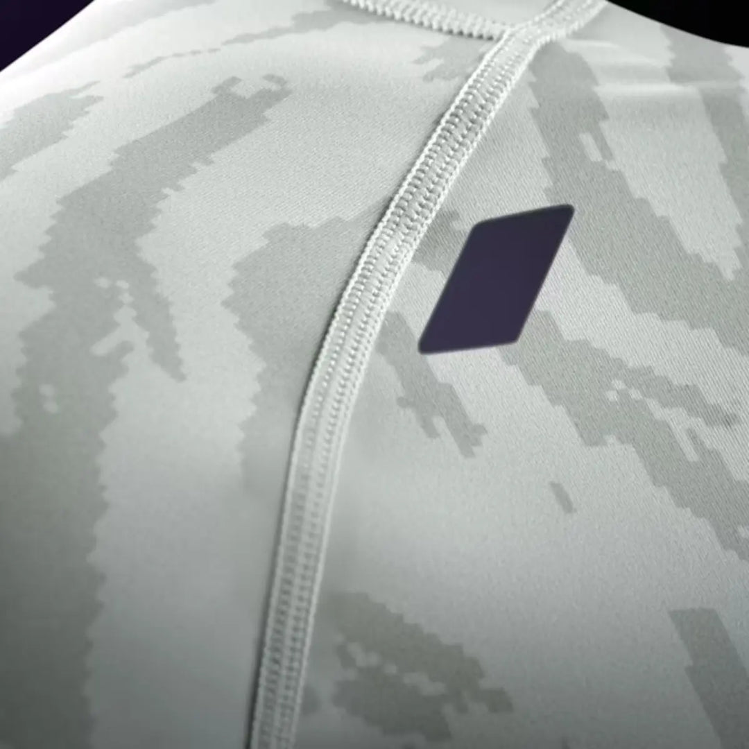 Close-up van de Hayabusa Apex short sleeve rashguard dames in stone beige, met zichtbare stiknaden en donkerpaars geometrisch detail op de borst
