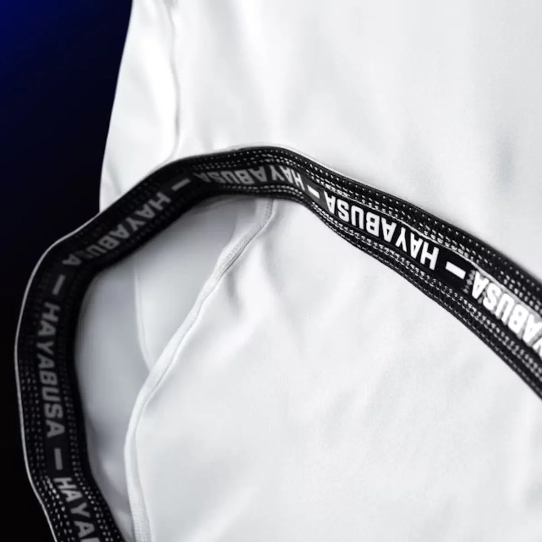 Close-up van de binnenkant van de Hayabusa Apex dames rashguard korte mouw in Ash White, met elastische band en zwart-wit Hayabusa-logo.