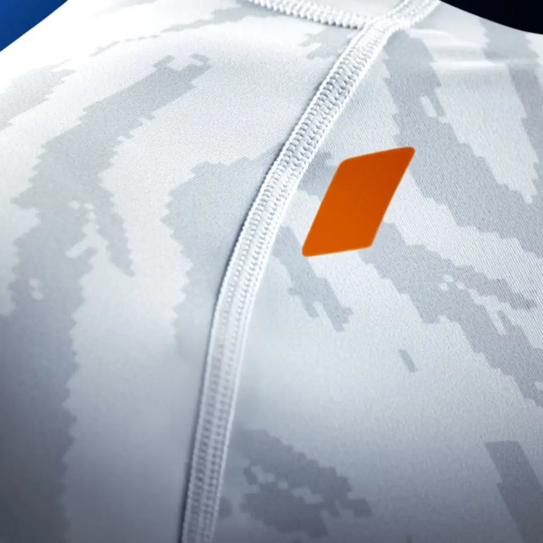 Detail van de borst van de Hayabusa Apex dames rashguard korte mouw in Ash White, met grijs camo-patroon en oranje Hayabusa-accent.