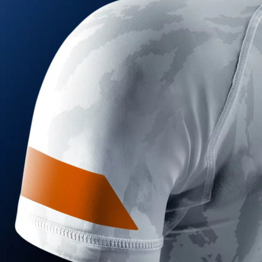 Close-up van de mouw van de Hayabusa Apex dames rashguard korte mouw in Ash White, met grijs camo-patroon en oranje detailaccent.