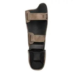 Binnenzijde van een gouden kickboks scheenbeschermer met zwarte voering en dubbele klittenbandsluiting, ontworpen voor stevige grip en comfort tijdens intensieve training.
