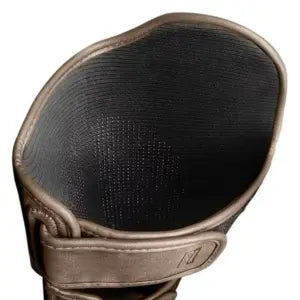 Binnenzijde van een gouden kickboks scheenbeschermer met zwarte antislipvoering en klittenbandsluiting, ontworpen voor extra grip en stabiliteit tijdens het sparren.