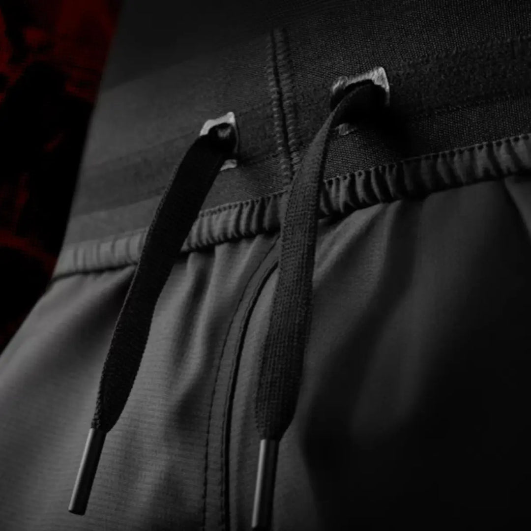 Close-up van de vetersluiting aan de taille van de UFC BJJ Women’s Shorts. De zwarte koorden met stevige afwerking laten de verstelbare pasvorm zien. De elastische tailleband biedt stabiliteit tijdens beweging. De donkere sfeer geeft de foto een professionele uitstraling.