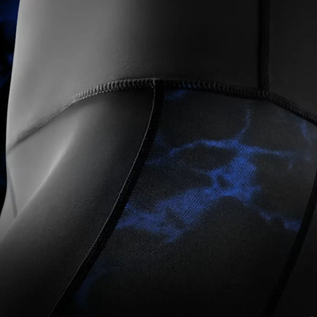 Close-up van de zijpanelen van de zwarte UFC BJJ Women’s Vale Tudo Shorts met blauw marmerpatroon. De naden en de compressiestof zijn duidelijk zichtbaar en tonen de nauwsluitende pasvorm. De afbeelding benadrukt de premium afwerking en flexibiliteit van het materiaal.