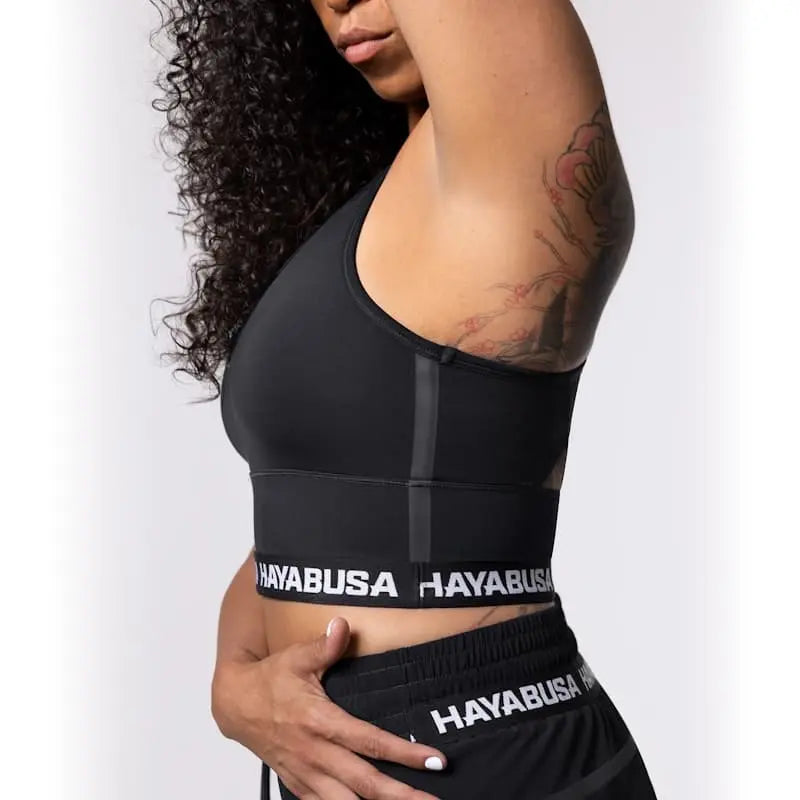 Close-up van de Hayabusa Sport BH Zwart die de strakke pasvorm en elastische band met Hayabusa-logo toont. De afbeelding laat zien hoe de sport-bh ondersteuning en comfort biedt tijdens intensieve bokstraining en kickbokstraining.