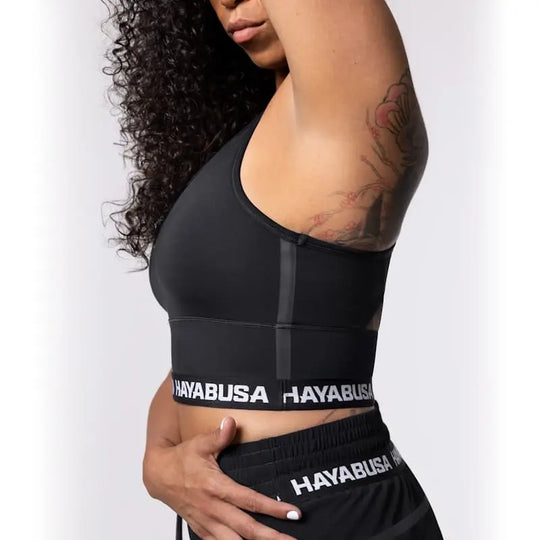 Close-up van de Hayabusa Sport BH Zwart die de strakke pasvorm en elastische band met Hayabusa-logo toont. De afbeelding laat zien hoe de sport-bh ondersteuning en comfort biedt tijdens intensieve bokstraining en kickbokstraining.